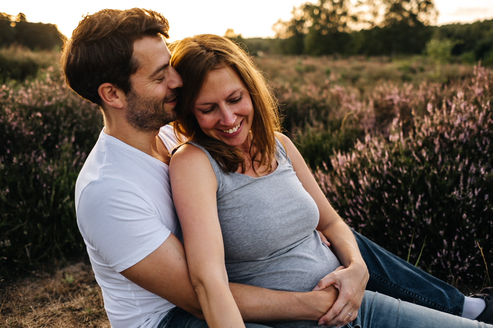 Schwangere Frau kuschelt sich an Mann Babybauchshooting