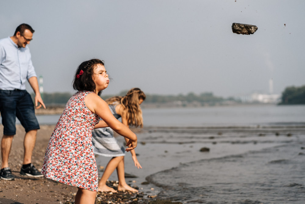 Familienfotografie in der Natur Kind wirft Stein ins Wasser