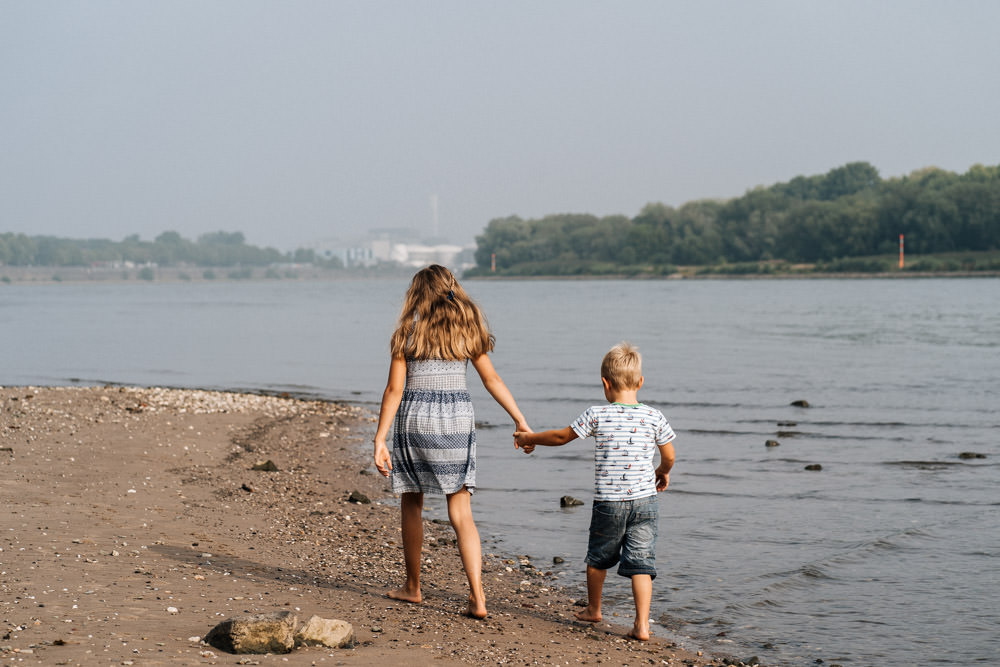 Schwester und Bruder spazieren am Strand