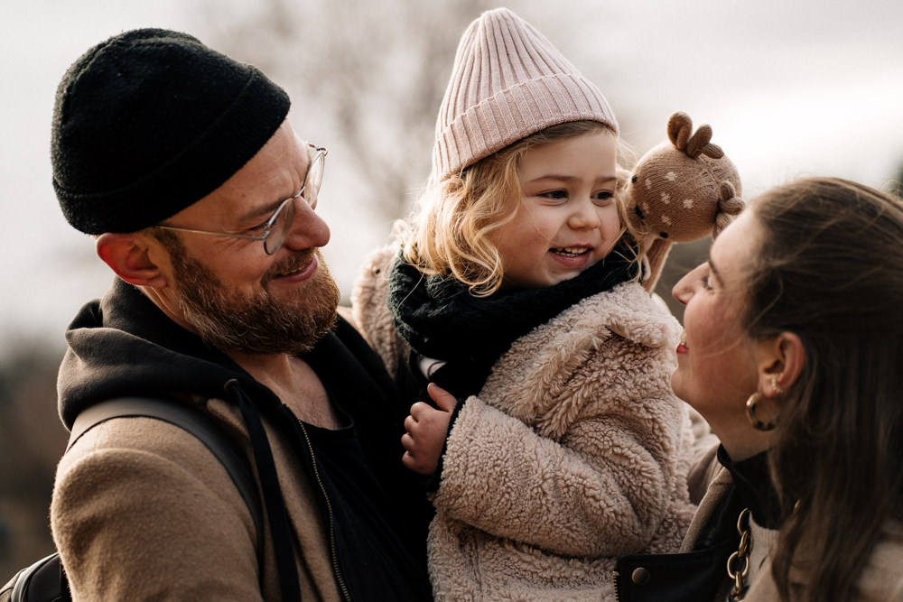 Tochter bei Mama und Papa auf dem Arm familienreportage